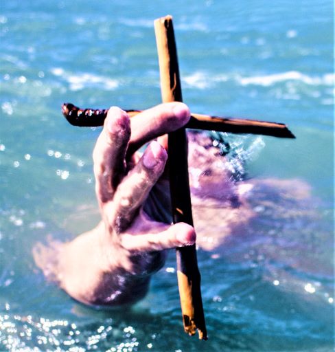 Hand holding cross in water